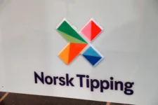 Bildet viser Norsk Tipping-logoen med fire fargerike geometriske former over firmanavnet i mørkeblå tekst, som representerer Norges spillemonopol, på hvit bakgrunn.