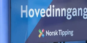 Et blått skilt med ordet «Hovedinngang» og logoen og teksten til Norsk Tipping, et norsk lotteriselskap som for tiden står overfor en norsk tipping-tillitskrise.